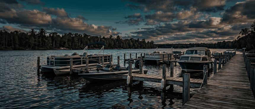 Pontoon and bass boats in their slips at a lake marina at first light